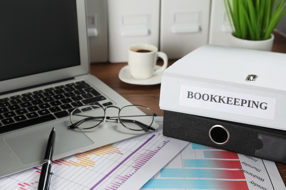Organized bookkeeping records, financial charts, and a labeled bookkeeping storage box on a professional desk